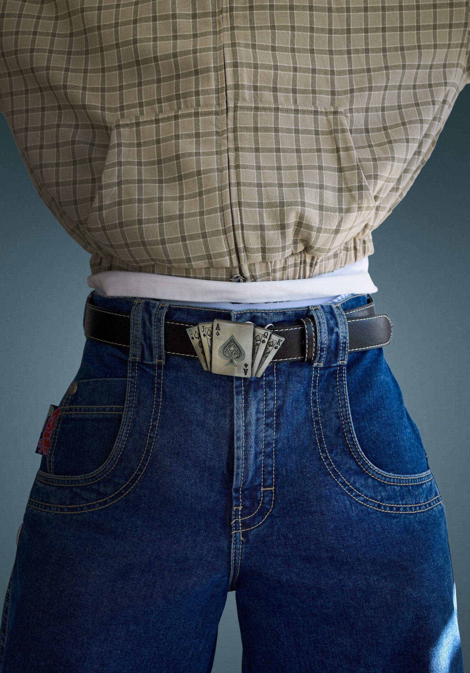 Model wearing a black belt with a silver playing-card buckle over baggy jeans