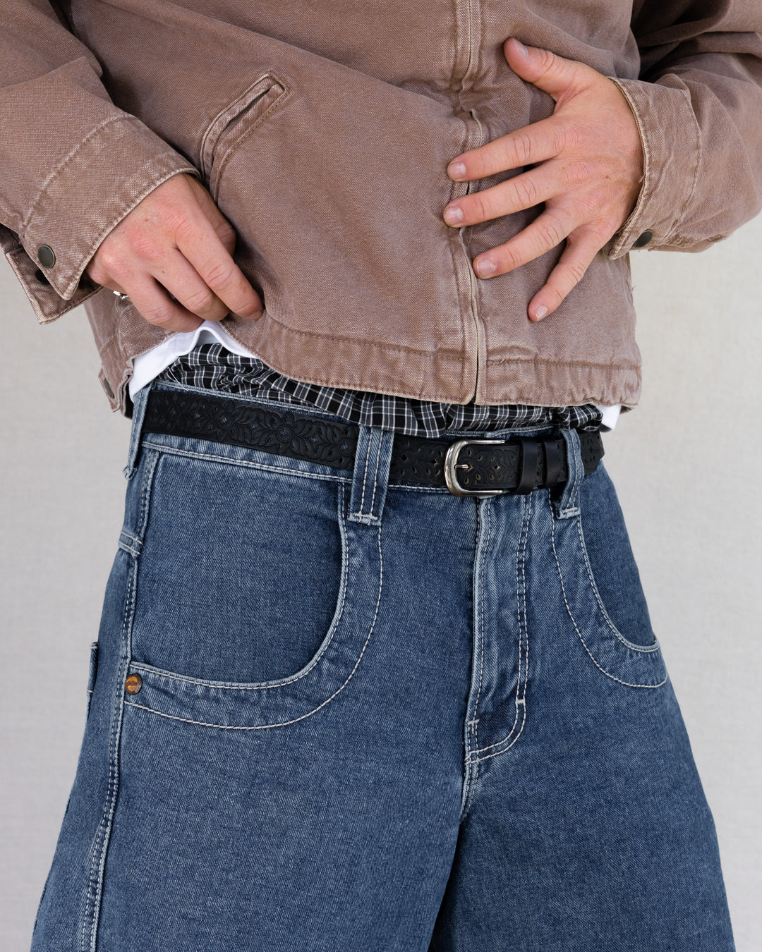 Rynor Carved Floral Belt – black belt with cutout-style tooling and metal buckle, worn by a model
