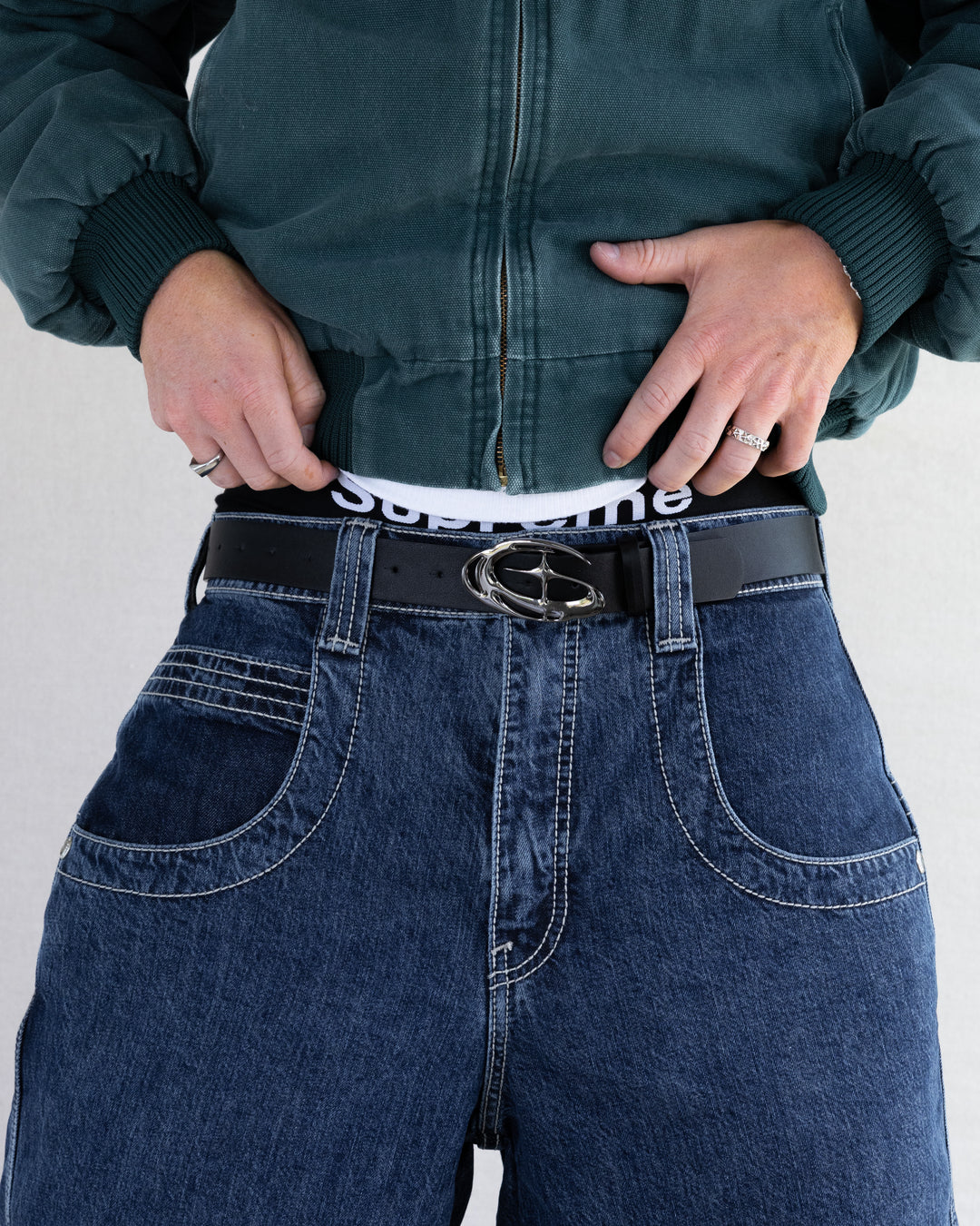 Rynor Orbit Chrome Buckle Belt – black belt with sculpted chrome buckle, worn by a model