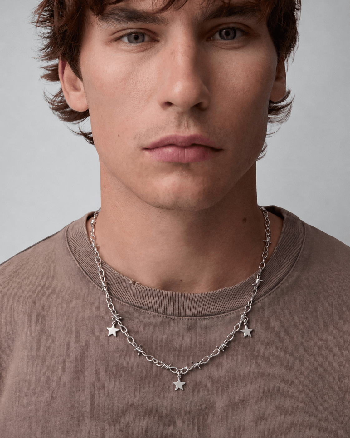 Rynor Star Charm Barbed Necklace – silver barbed wire chain necklace with hanging star charms, worn by a model