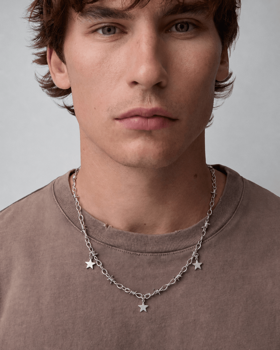 Rynor Star Charm Barbed Necklace – silver barbed wire chain necklace with hanging star charms, worn by a model