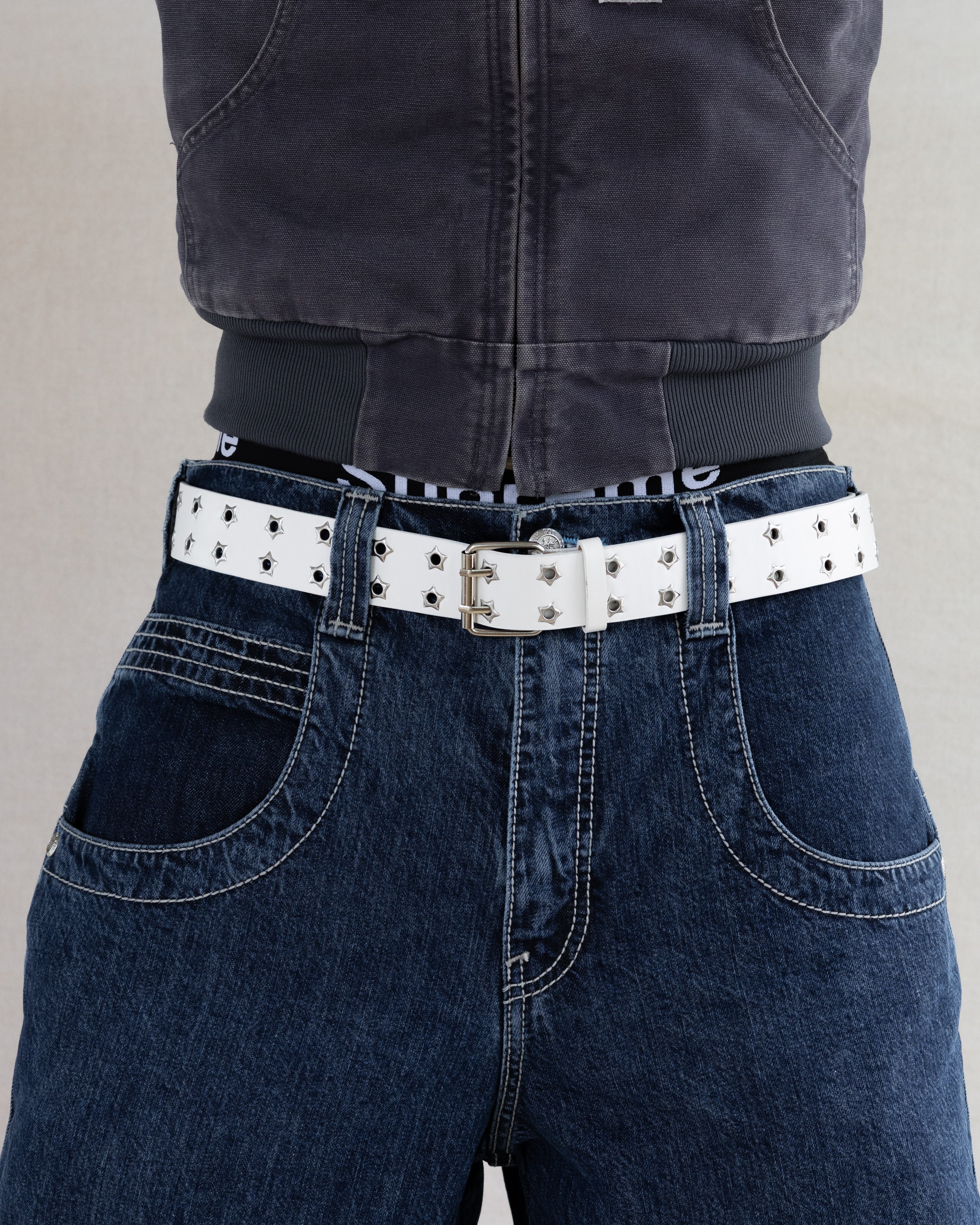 Rynor Starforge Belt – white leather belt with star-shaped grommets and double-prong buckle, worn by a model